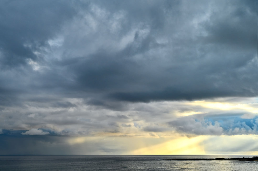Dramatic sunrays coming from storm clouds over the ocean. Photograph by Christina Stefani.